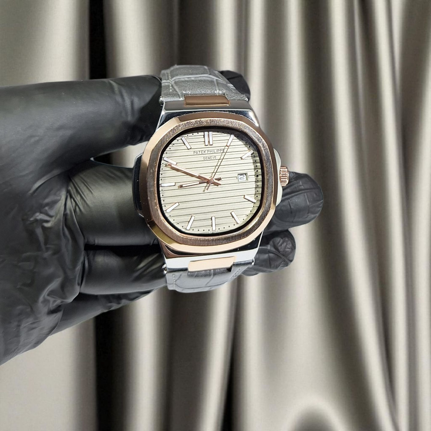 Luxury watch held by a gloved hand against a neutral background
