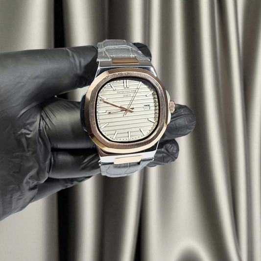 Luxury watch held by a gloved hand against a neutral background