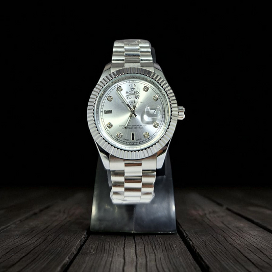 Silver watch with a dark face on a wooden stand against a black background